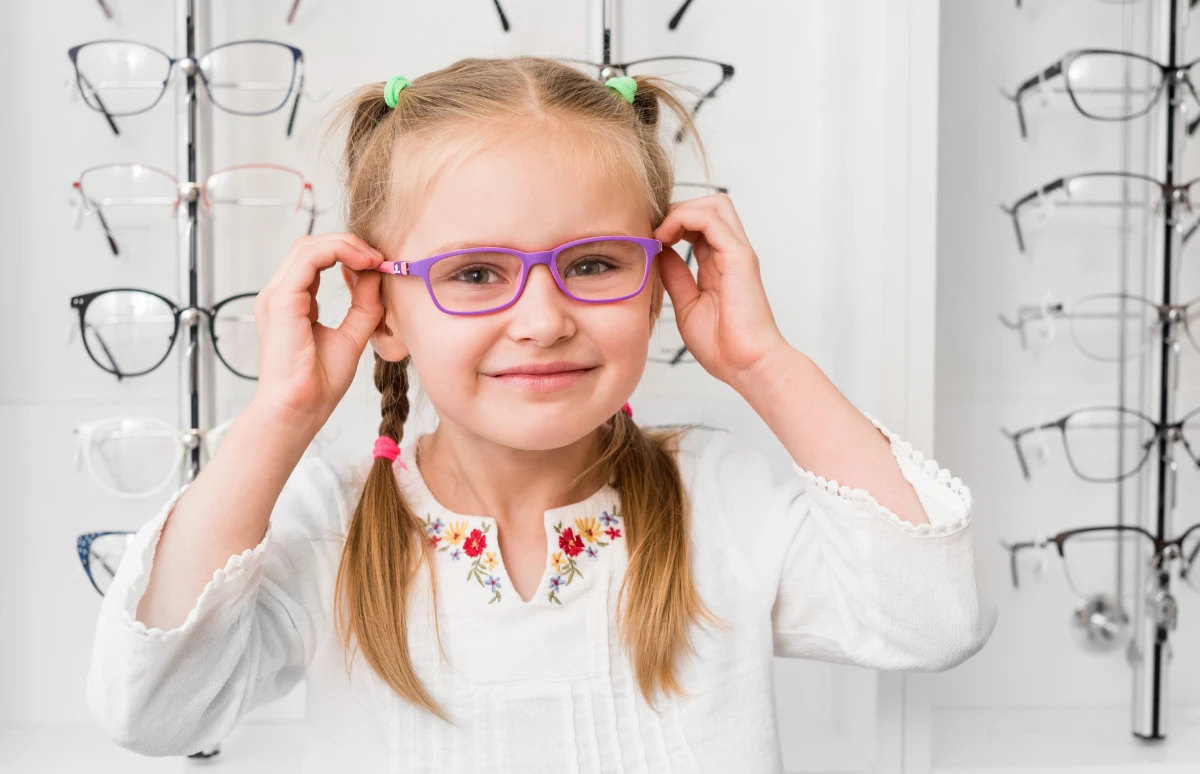 Okulary korekcyjne dla dziecka Poznań, dziewczynka przymierza okulary z kolorową oprawką Okulary korekcyjne dla dziecka Poznań, dziewczynka przymierza okulary z kolorową oprawką