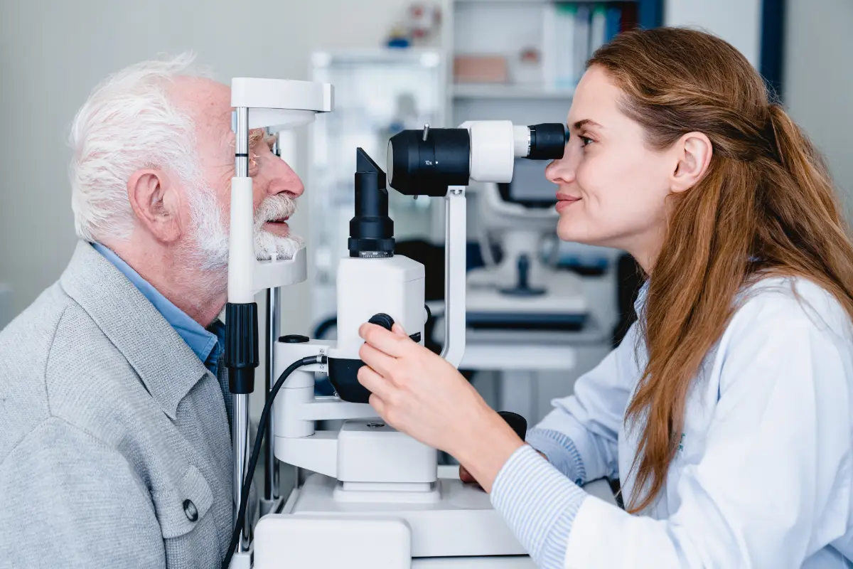 Sprawadzanie wzroku u starszego pana przy pomocy urządzenia do badania dna oka